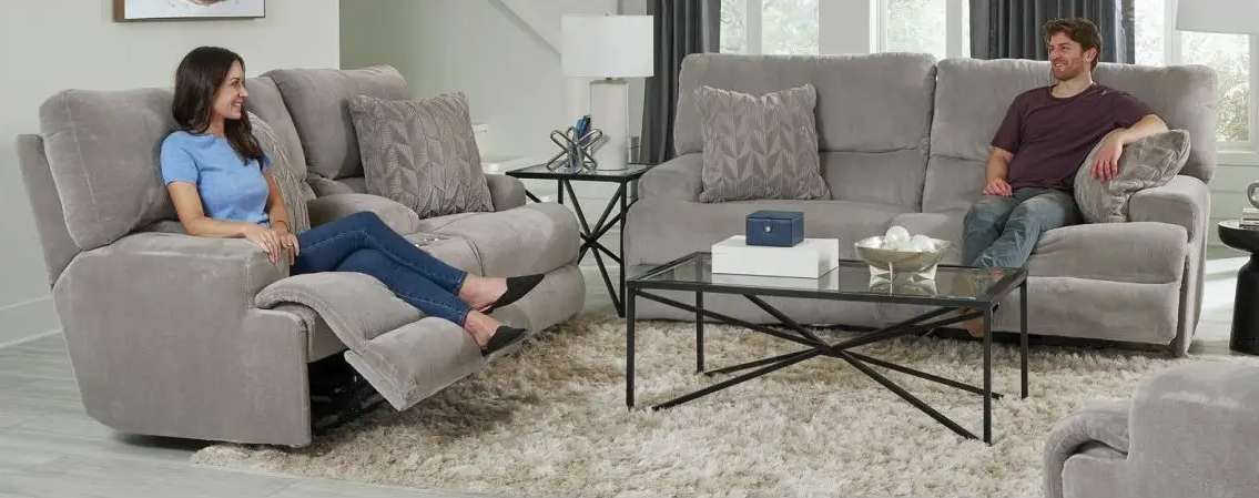 Two people relaxing on grey sofas.